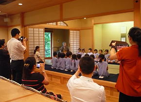 The participants are fascinated by the sight of kindergarten children practicing the traditional tea ceremony. The group visited the Hibarigaoka Gakuen school, which has a kindergarten and elementary, junior-high and high schools at a single site.