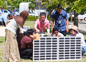Practical training takes place under the blazing sun. The seminar participants measure voltage and current while under the guidance of Japanese and third-country specialists.