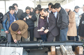 With great interest, the participants inspect a cast-iron joint from a pipe with properties that allow it to expand and contract and which is used by Osaka City’s Waterworks Bureau to repair leaks.