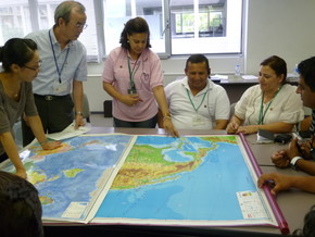 Seminar participants stand around a large map of the world, explaining each of their backgrounds. This was an icebreaking activity so that we could form good teams.